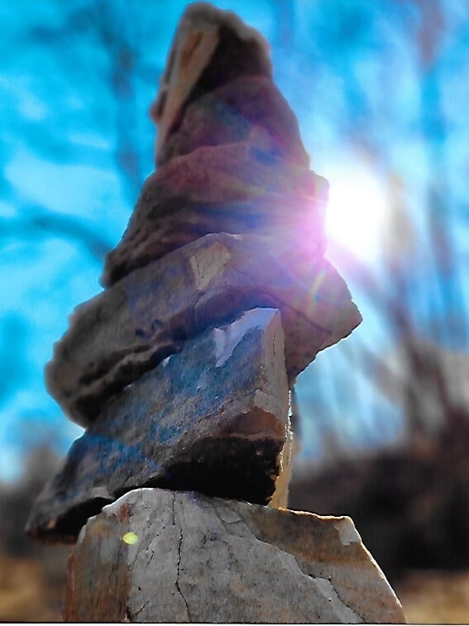 rocks stacked with the sun peeking out from behind